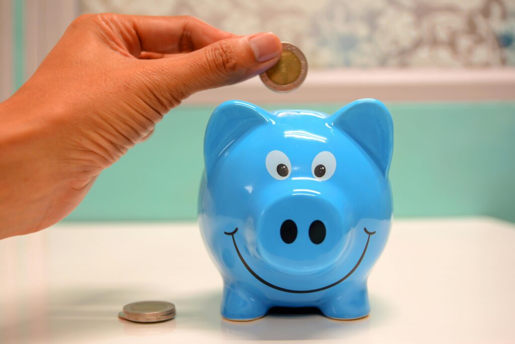 Mutual Funds Hand inserting a coin into a blue piggy bank for savings and money management.
